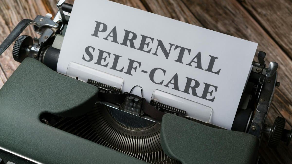 A vintage typewriter typing the phrase 'Parental Self-Care' on a wooden table.