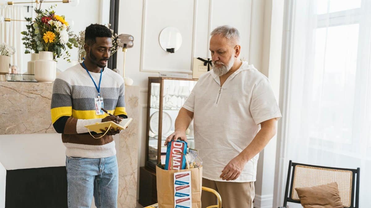Two male volunteers packing donation bags with essentials indoors.