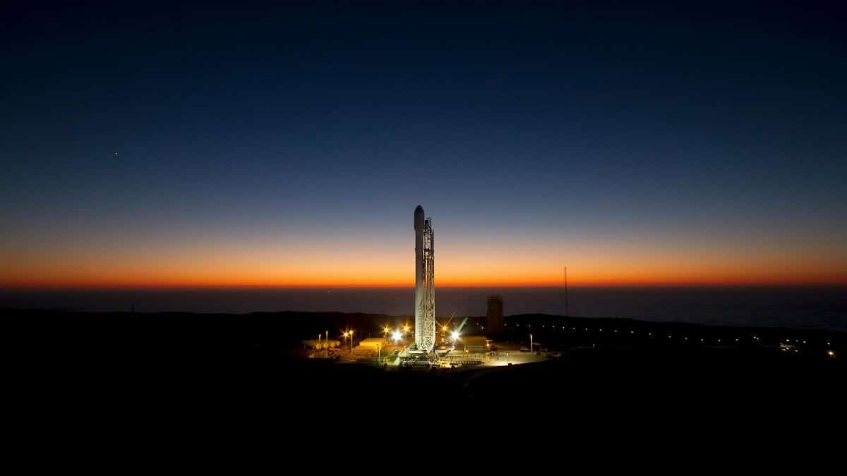 A powerful rocket stands ready on its launch pad against a stunning twilight sky.