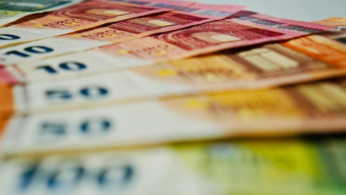 A close-up image of euro banknotes in various denominations spread out, showcasing currency details.