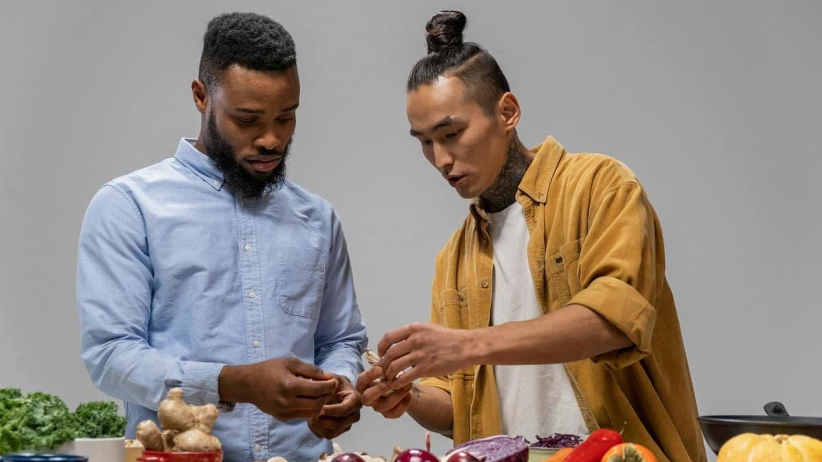Two men preparing vegetables for a healthy meal, emphasizing diversity and teamwork.