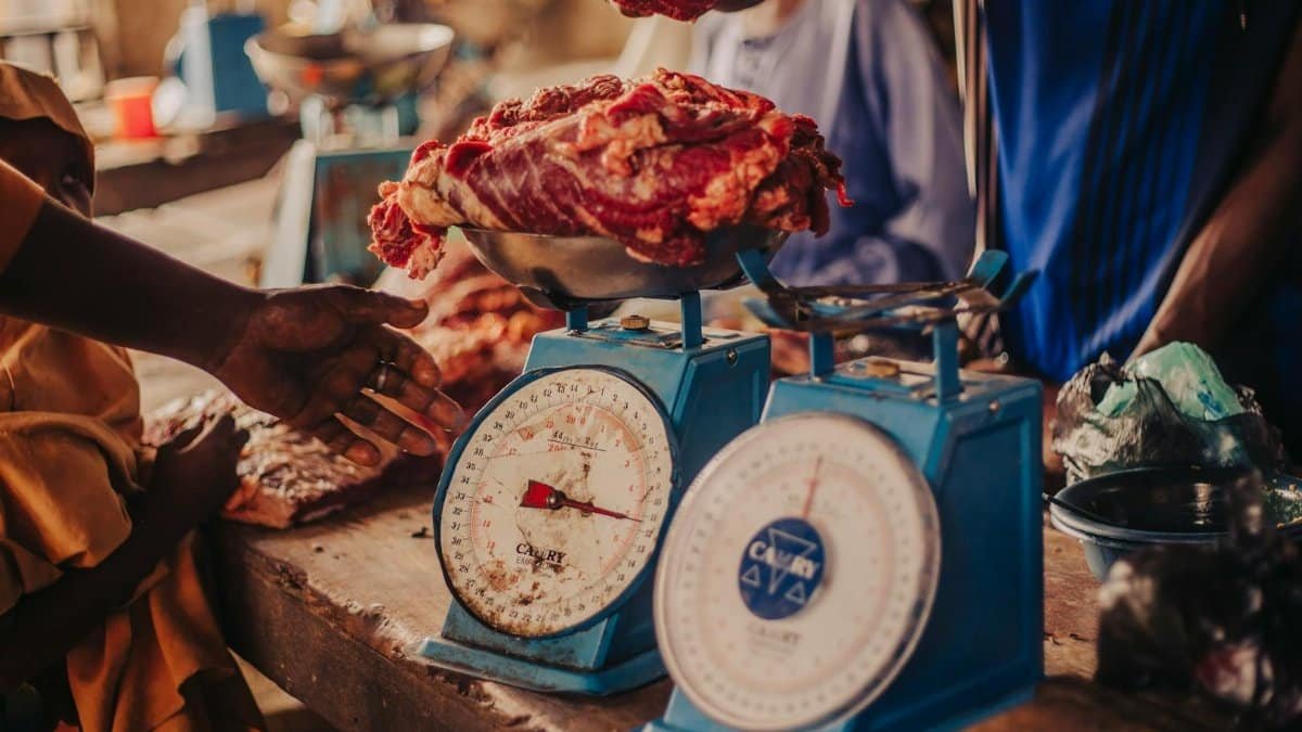 A bustling market with fresh meat being weighed on traditional scales.