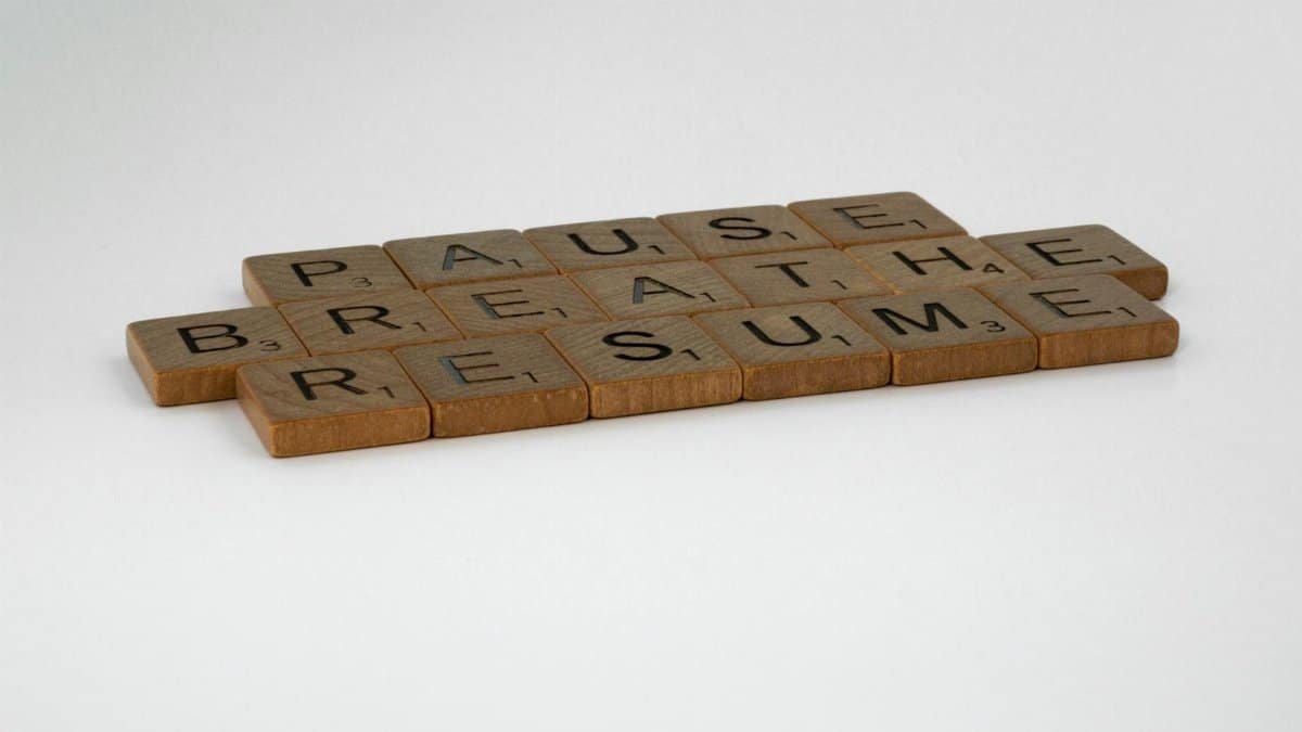 Scrabble tiles spelling 'Pause, Breathe, Resume' on a white background, symbolizing mindfulness and relaxation.