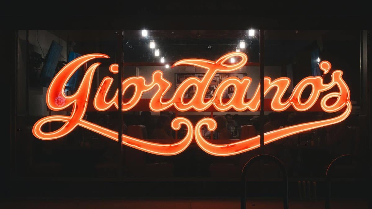 A vibrant neon Giordano's sign glowing at night, capturing urban nightlife.