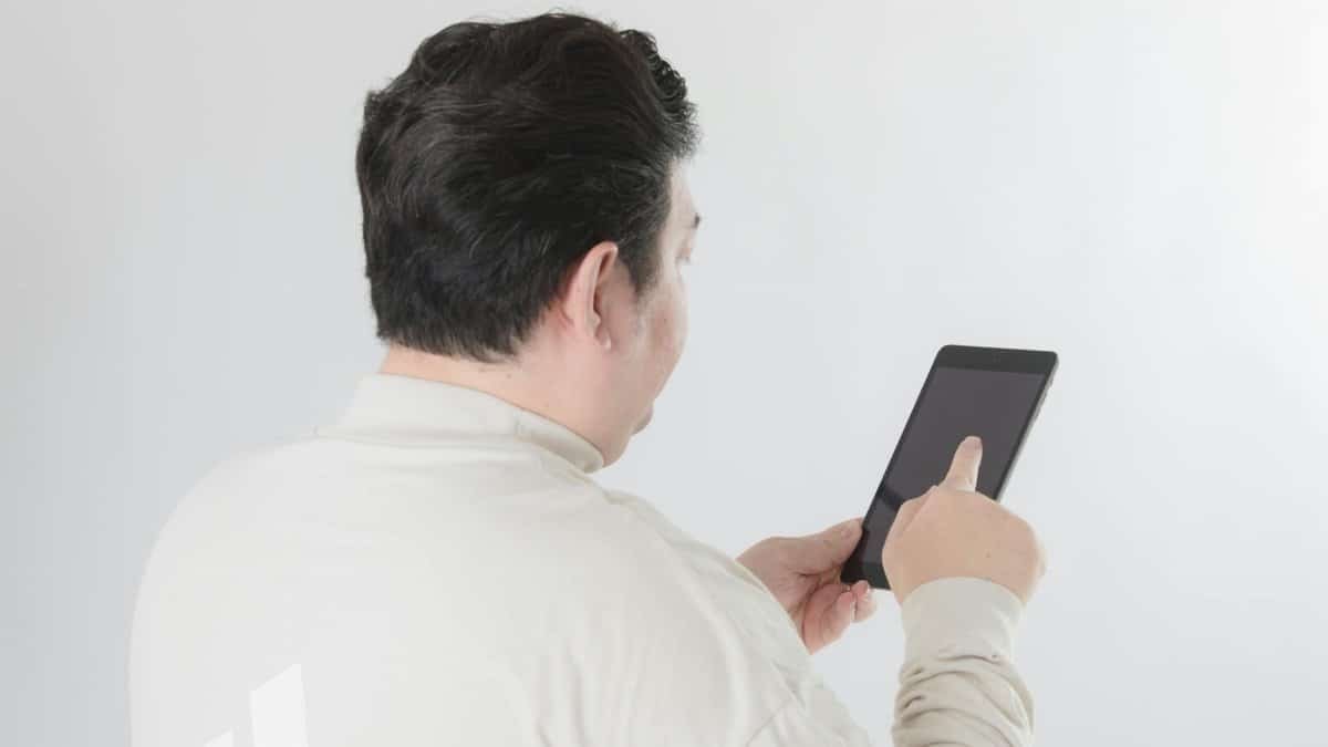 Rear view of a man with black hair using a tablet. Ideal for technology and lifestyle themes.