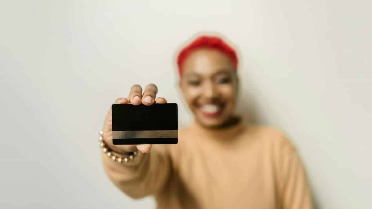 Close-up of a credit card held by a smiling person, emphasizing modern finance and personal identity.