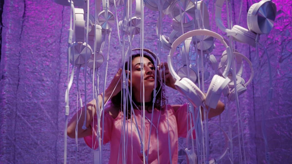 A woman enjoying music under a stunning violet headphone installation.