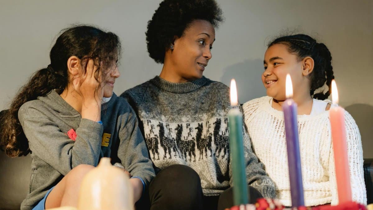 A joyful family gathering celebrating Kwanzaa with candles and smiles indoors.