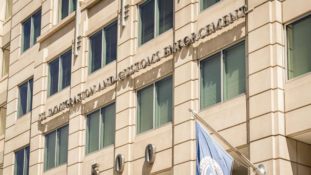Exterior view of the US Immigration and Customs Enforcement building with a visible flag and signage.