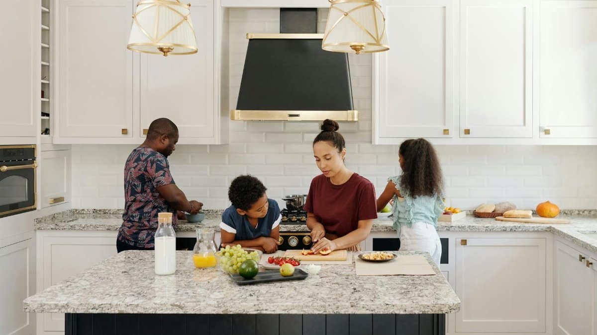 Family enjoying a cooking session together in a bright modern kitchen setting.
