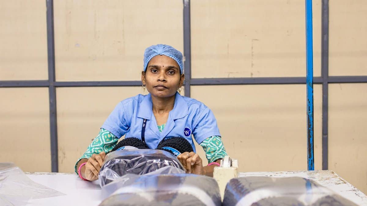 A dedicated female factory worker packaging textile rolls on a workbench.