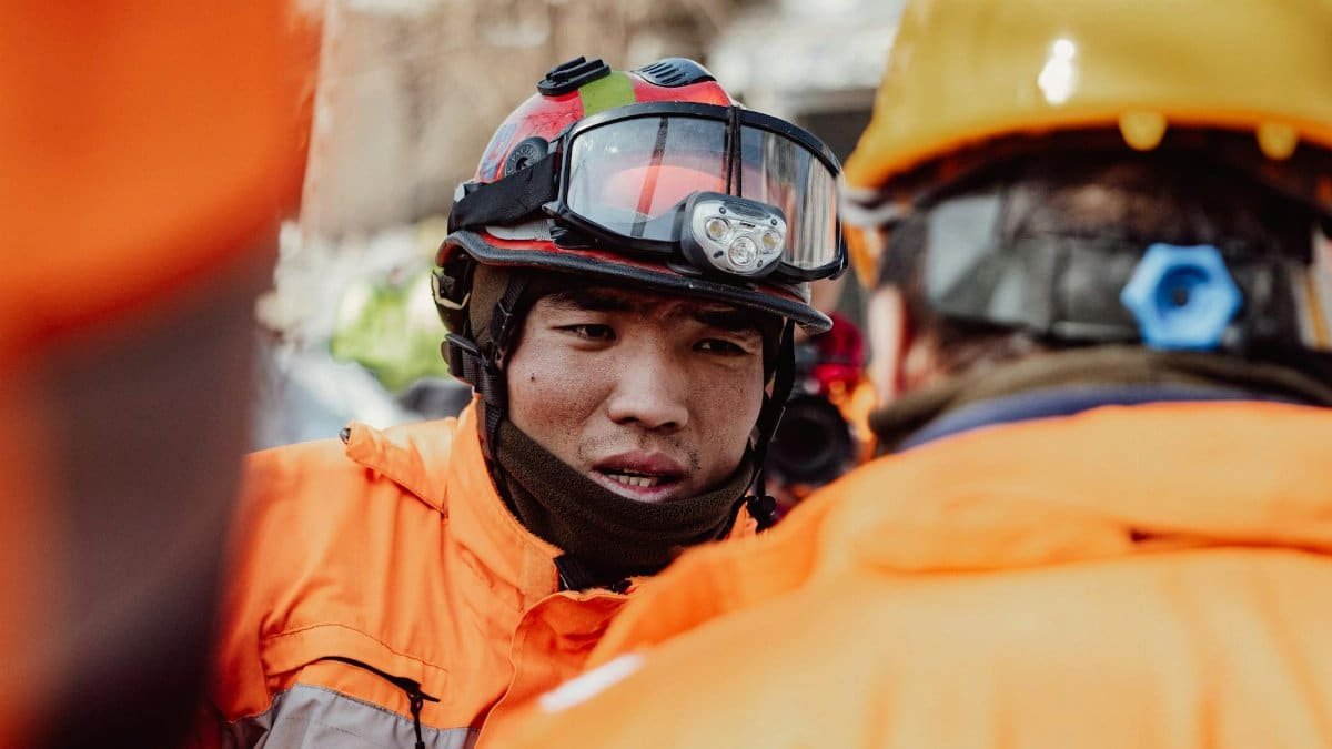 Two rescue workers in helmets and safety gear discussing the emergency response plan.
