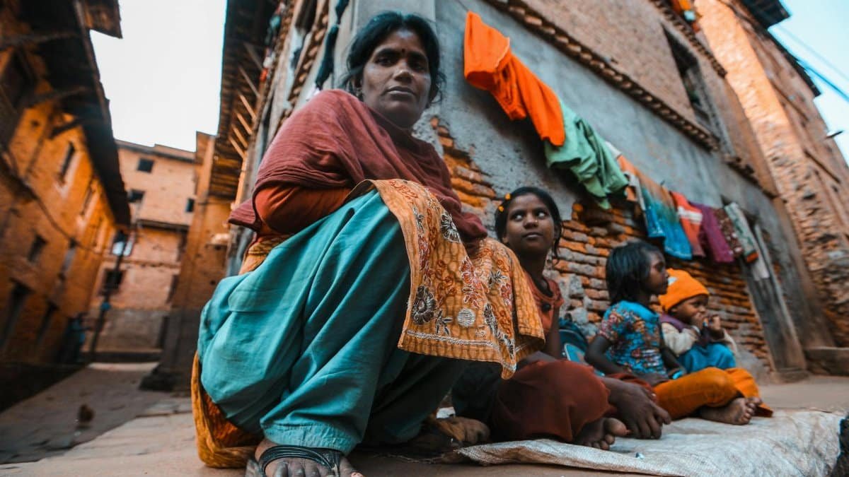 A family sits together in an alley, reflecting community life and cultural attire.