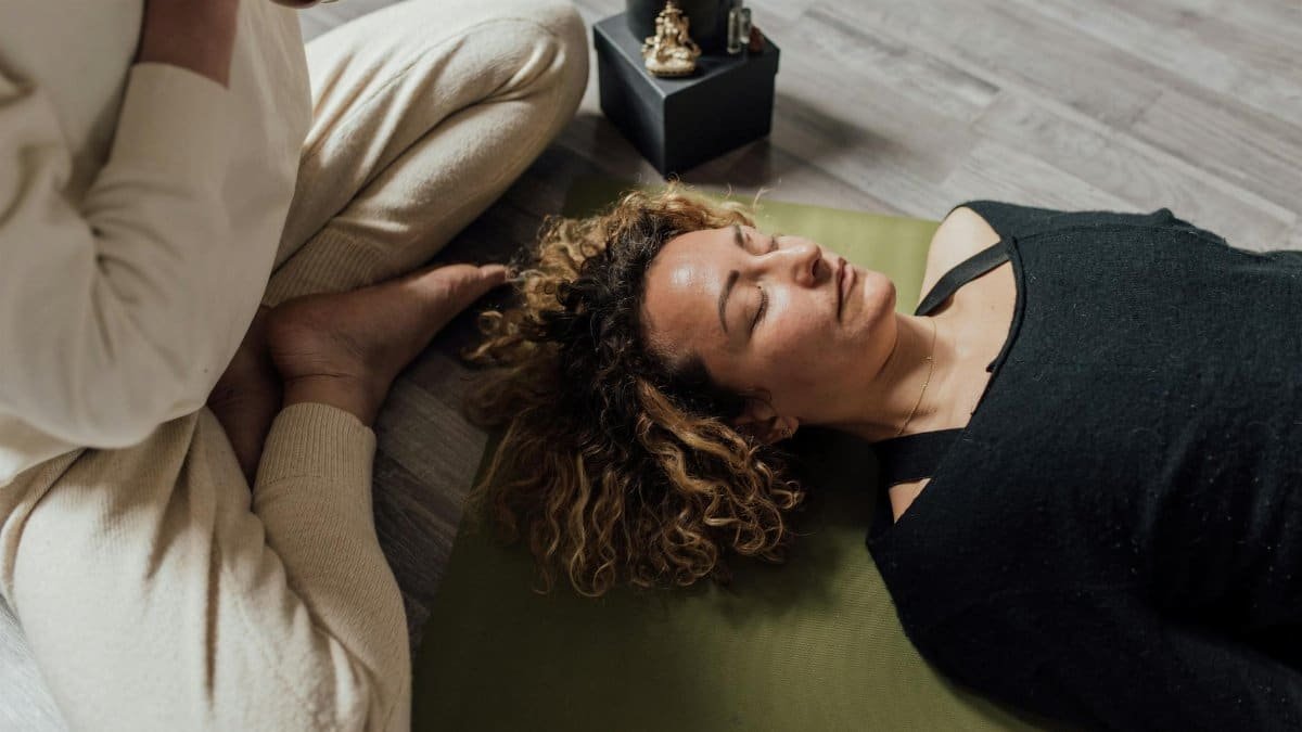 A woman meditating indoors on a yoga mat in a calm atmosphere.