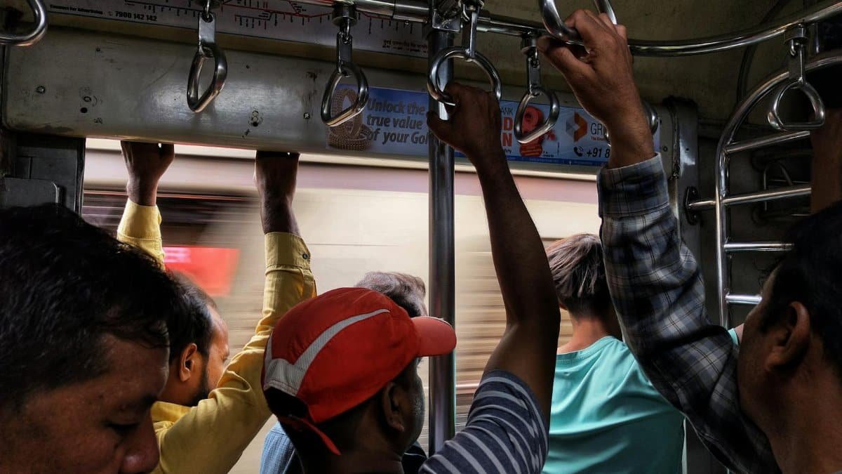 Passengers standing and holding handles inside a busy Mumbai local train.