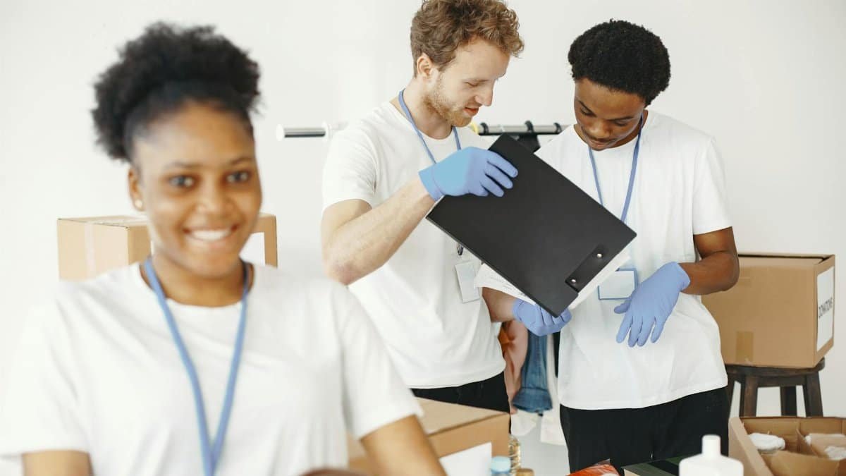 A diverse group of young volunteers organizing donations indoors with a cheerful atmosphere.
