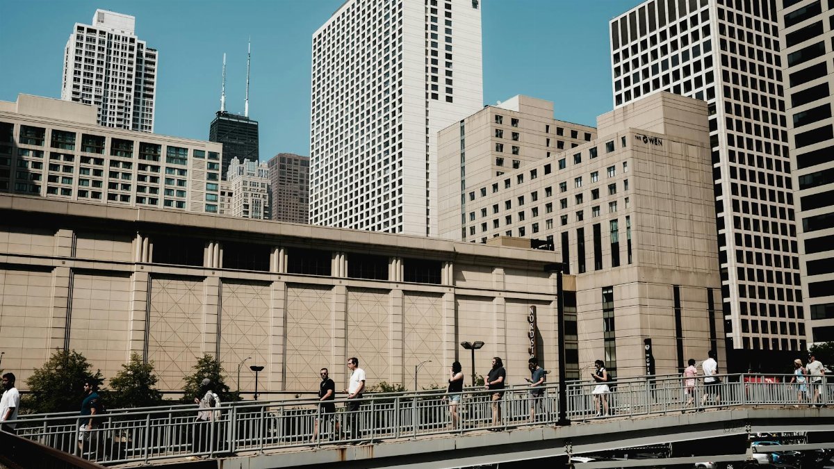 People crossing a bridge with the skyscrapers of Chicago's skyline in the background.