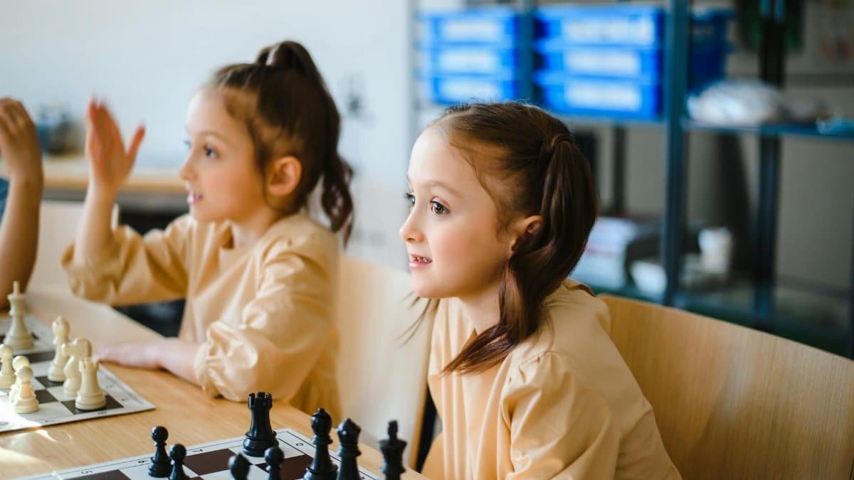 Two girls playing chess indoors, focusing on strategy and fun.
