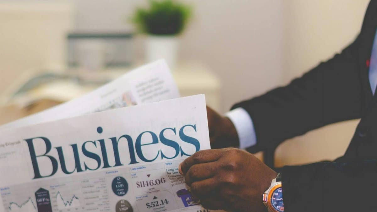 Close-up of a businessman reading a newspaper indoors, focusing on business headlines.