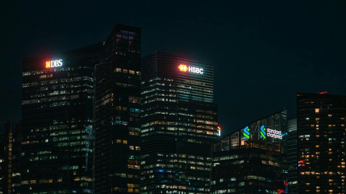Illuminated city skyscrapers of major banks in Singapore's financial district at night.