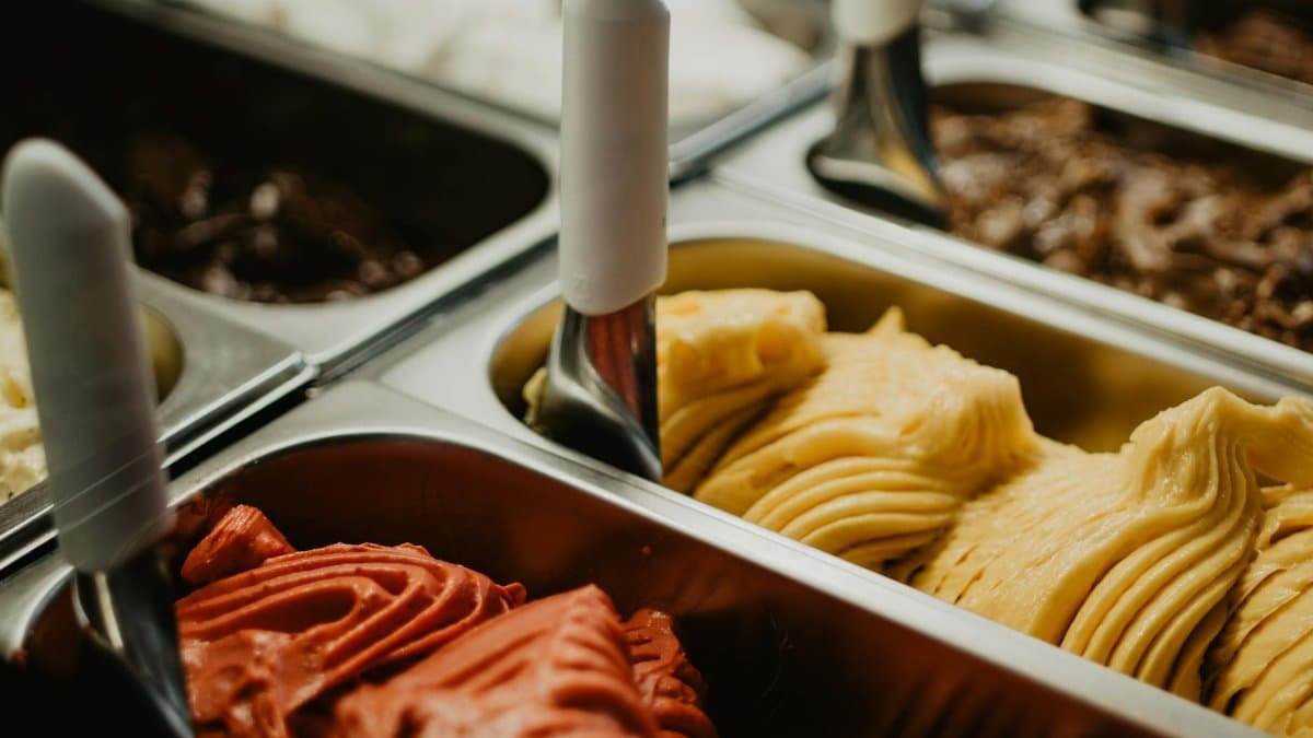 A vibrant display of colorful gelato flavors in metal trays at an ice cream shop.