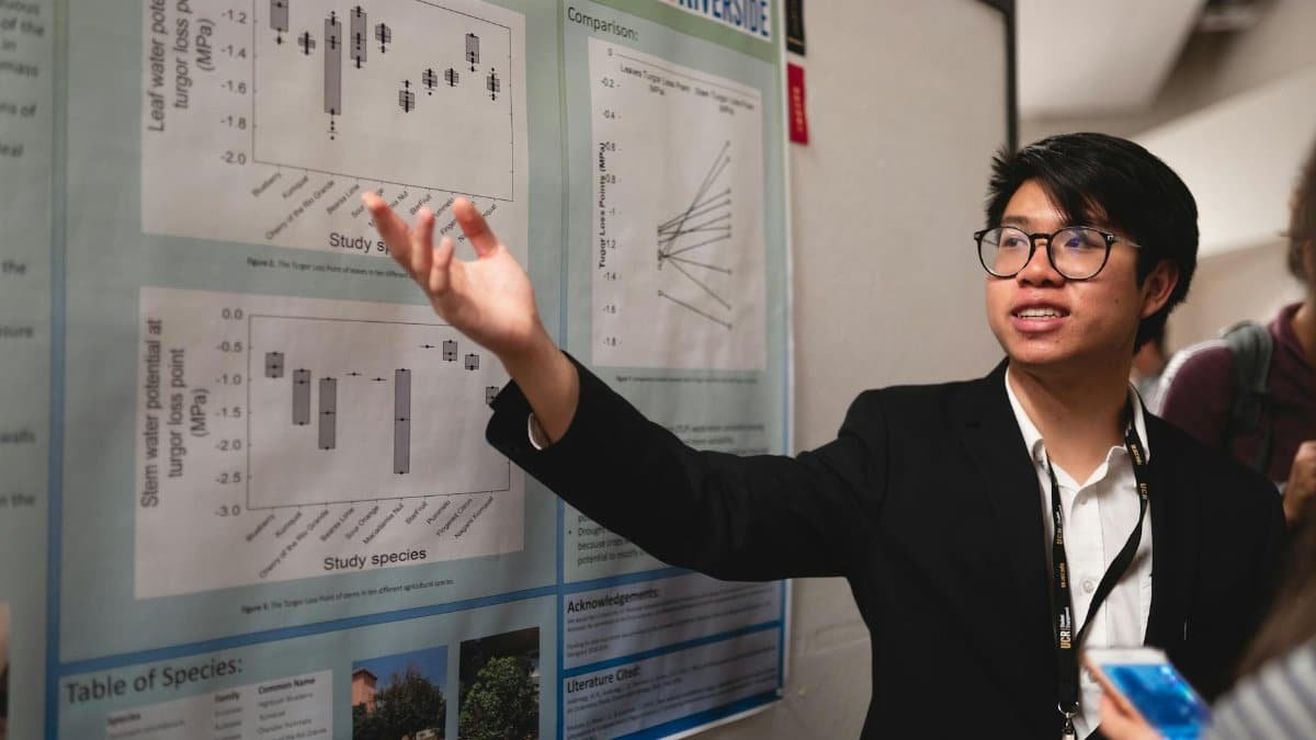 Asian man presenting scientific research on poster at UC Riverside.