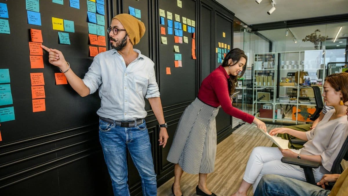 Team members collaborating in a modern office with sticky notes on a wall, focusing on brainstorming and strategy.