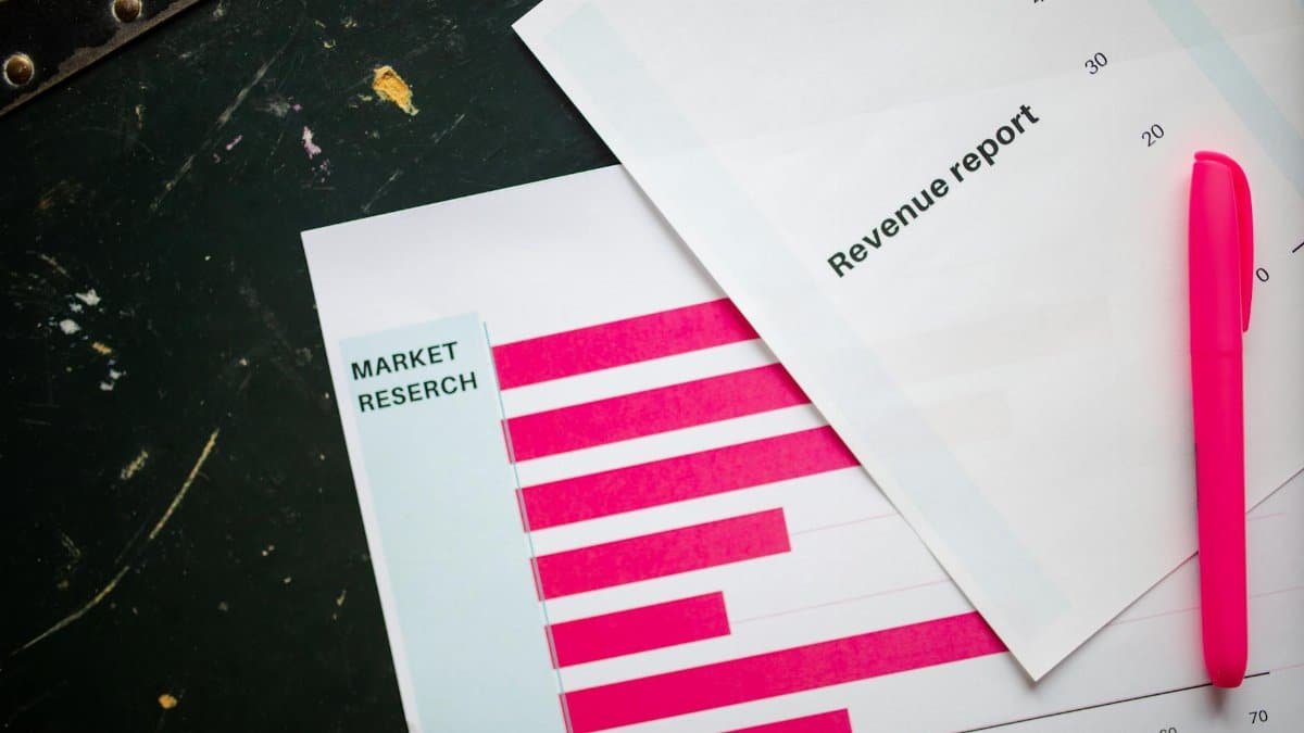 Close-up of market research charts and a revenue report with a pink pen on a desk.
