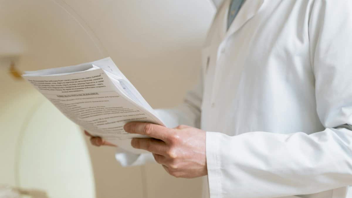 Doctor in a white coat examining medical papers in a healthcare setting.