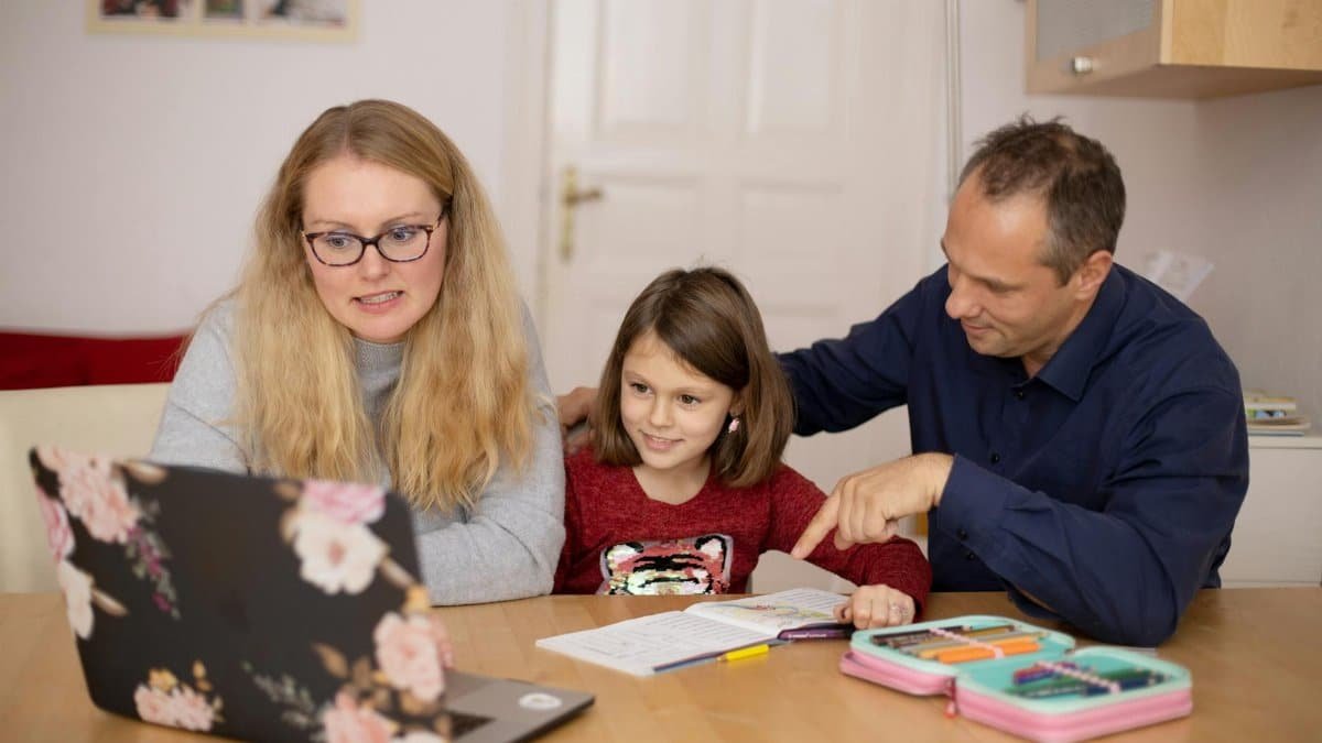 A family is engaged in homeschooling, using technology to learn together in a cozy home setting.