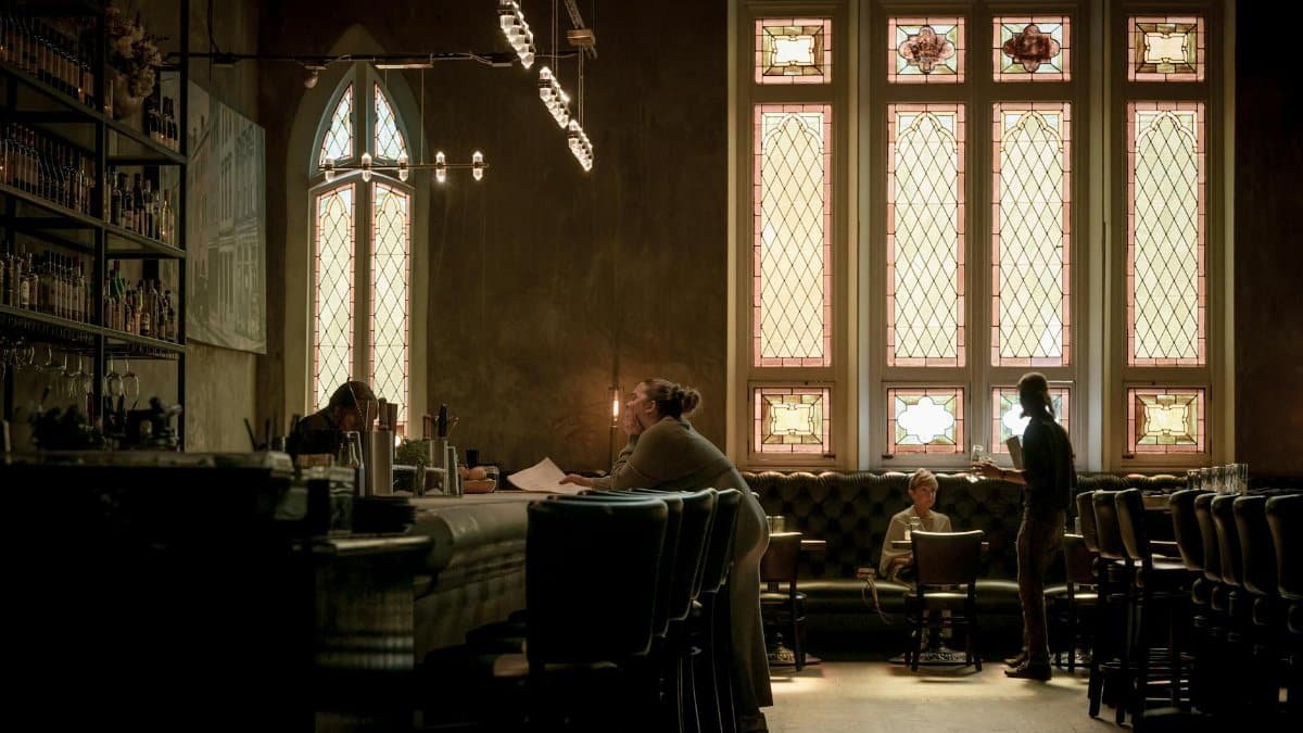 Elegant bar with stained glass windows and patrons, creating a cozy ambiance.