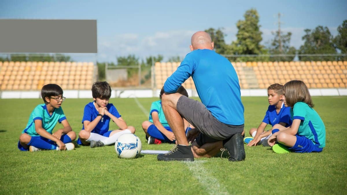 Group of kids receiving soccer coaching on a sunny day at a soccer field in Portugal.