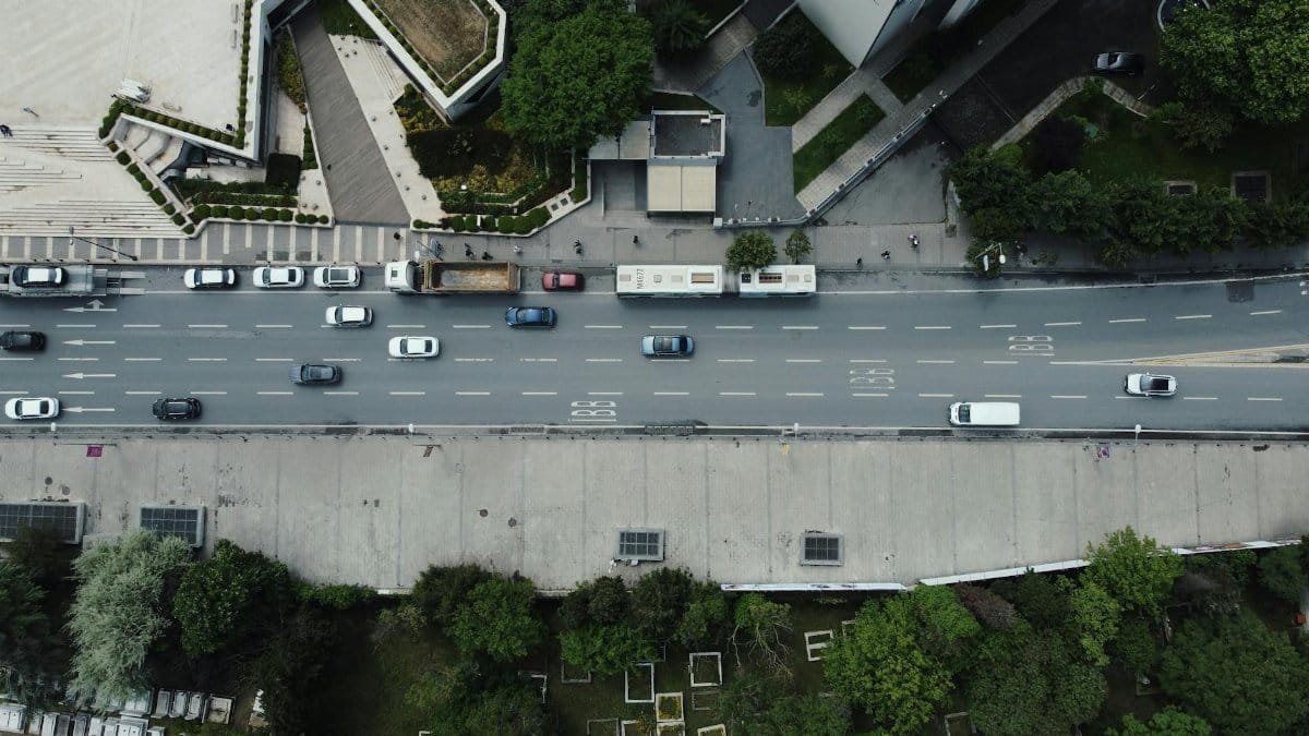 Overhead drone shot of a busy road in Istanbul, showing cars, buses, and greenery.