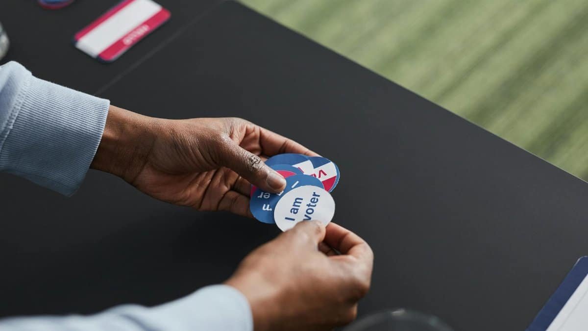 A close-up of hands holding voter stickers, symbolizing civic engagement.