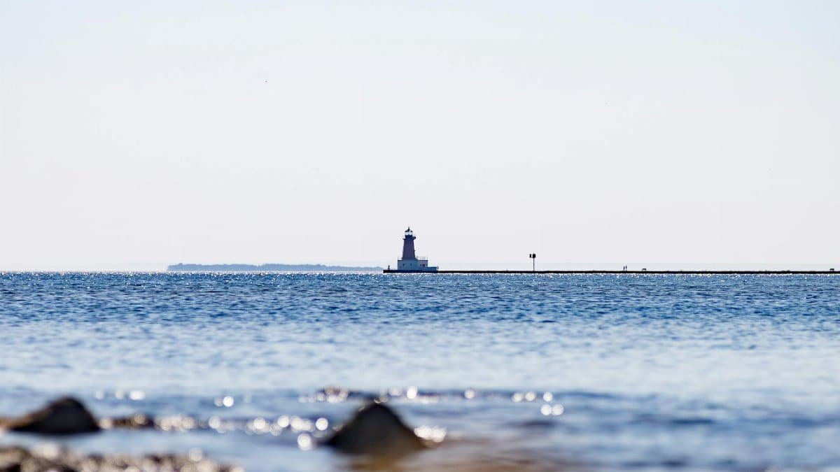 A serene view of Menominee North Pier Lighthouse across the shimmering blue water.