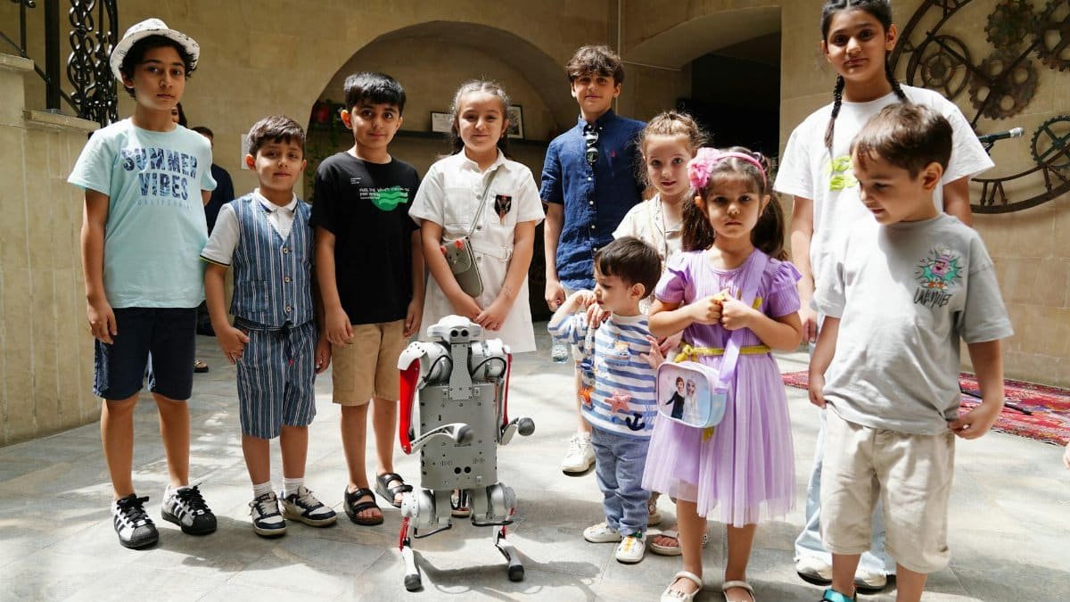A diverse group of children joyfully interacting with a humanoid robot indoors, showcasing future technology.