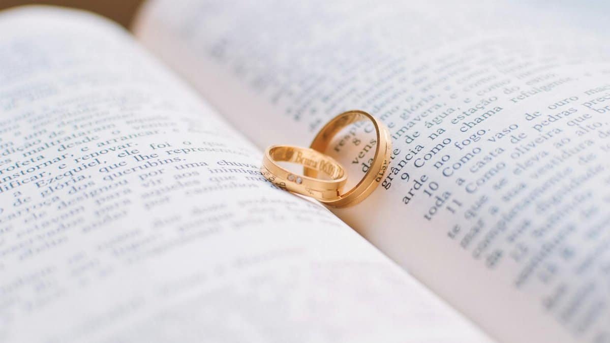 Close-up of wedding rings resting on the pages of an open book, symbolizing love and commitment.
