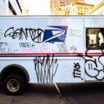 Graffiti-covered delivery truck parked in New York City street, showcasing urban art culture.