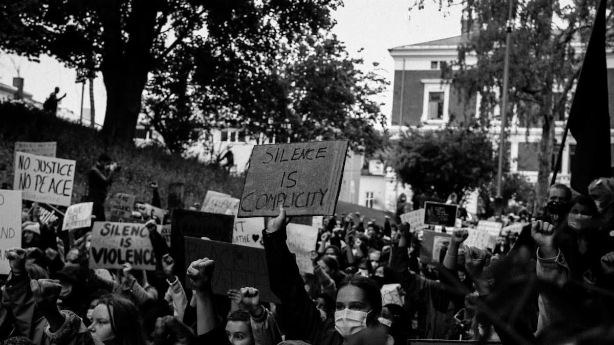 A powerful black and white image of a protest rally with signs demanding justice and peace.