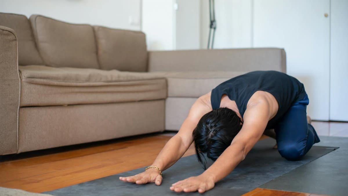 An adult man performs a calming yoga pose indoors, promoting a healthy lifestyle.