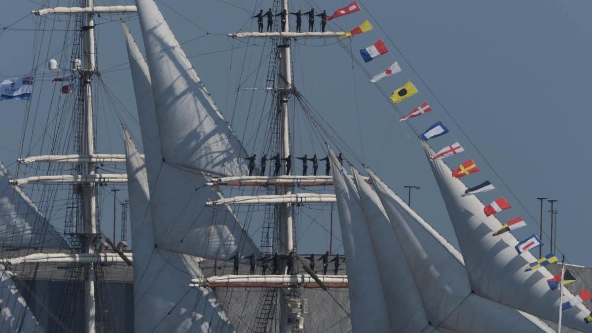 Crew members on a tall ship with sails and nautical flags in Bremerhaven, Germany.