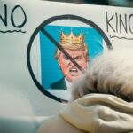 A protest sign reading 'No Kings' depicts resistance against monarchy with a satirical image.