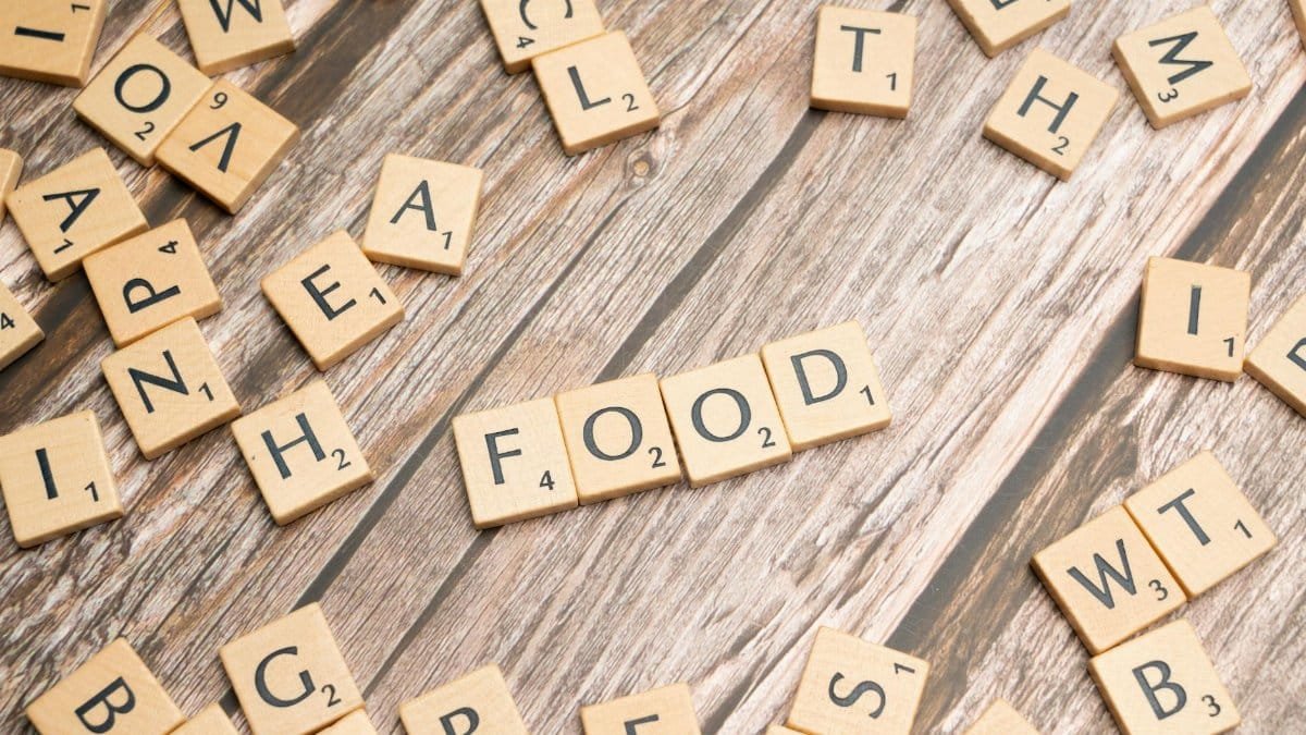 Wooden letter tiles spelling 'food' arranged on a rustic wooden surface, depicting culinary themes.