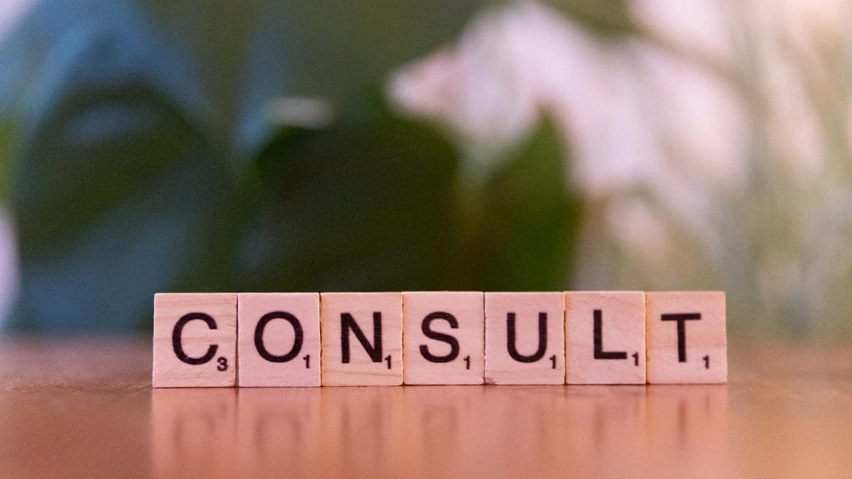 Scrabble tiles spelling 'CONSULT' on a wooden table with blurred background.