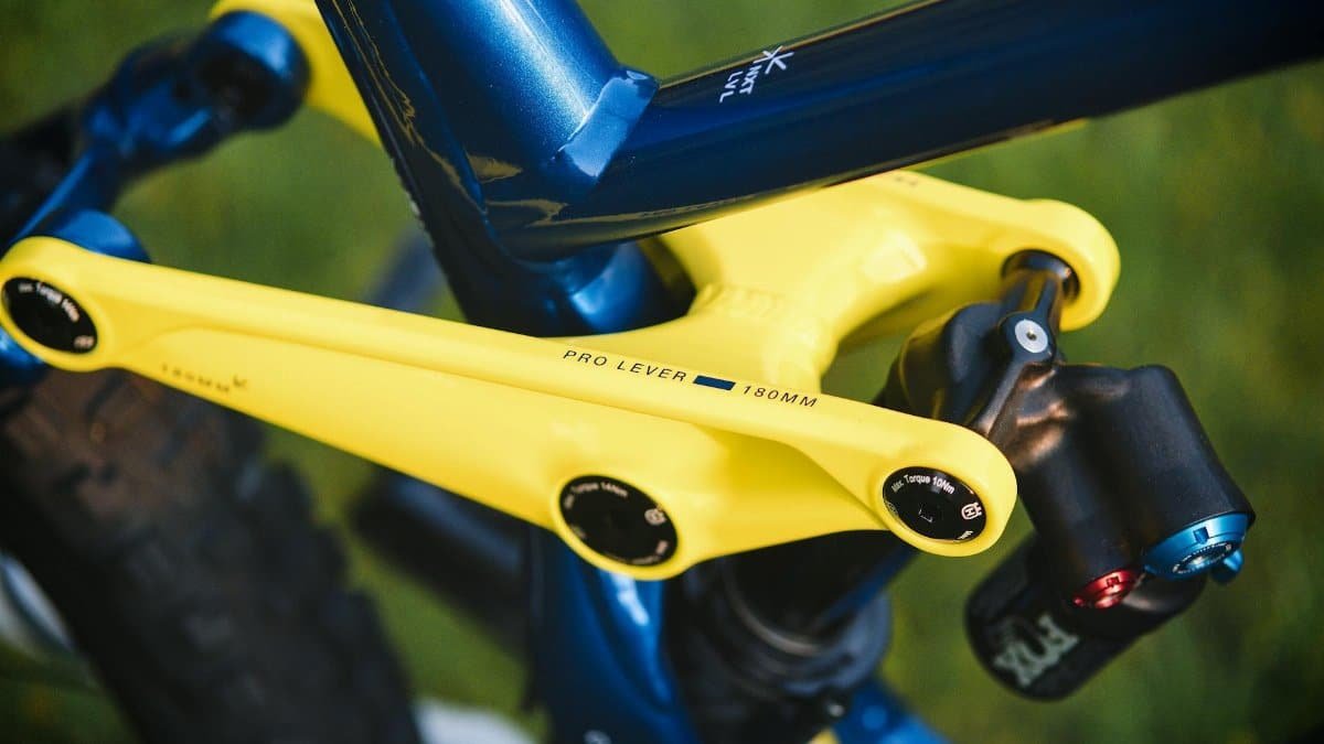 Detailed view of a mountain bike's yellow shock absorber arm and suspension system.