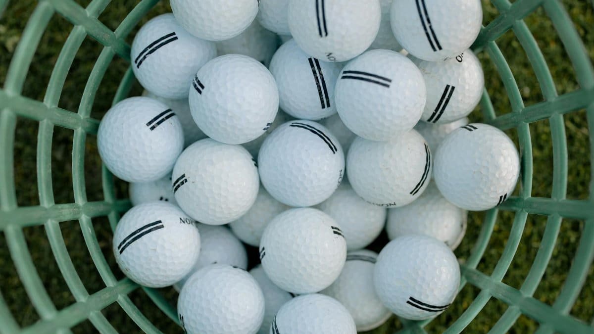 A high-angle view of golf balls in a basket on grass, illustrating golfing equipment.