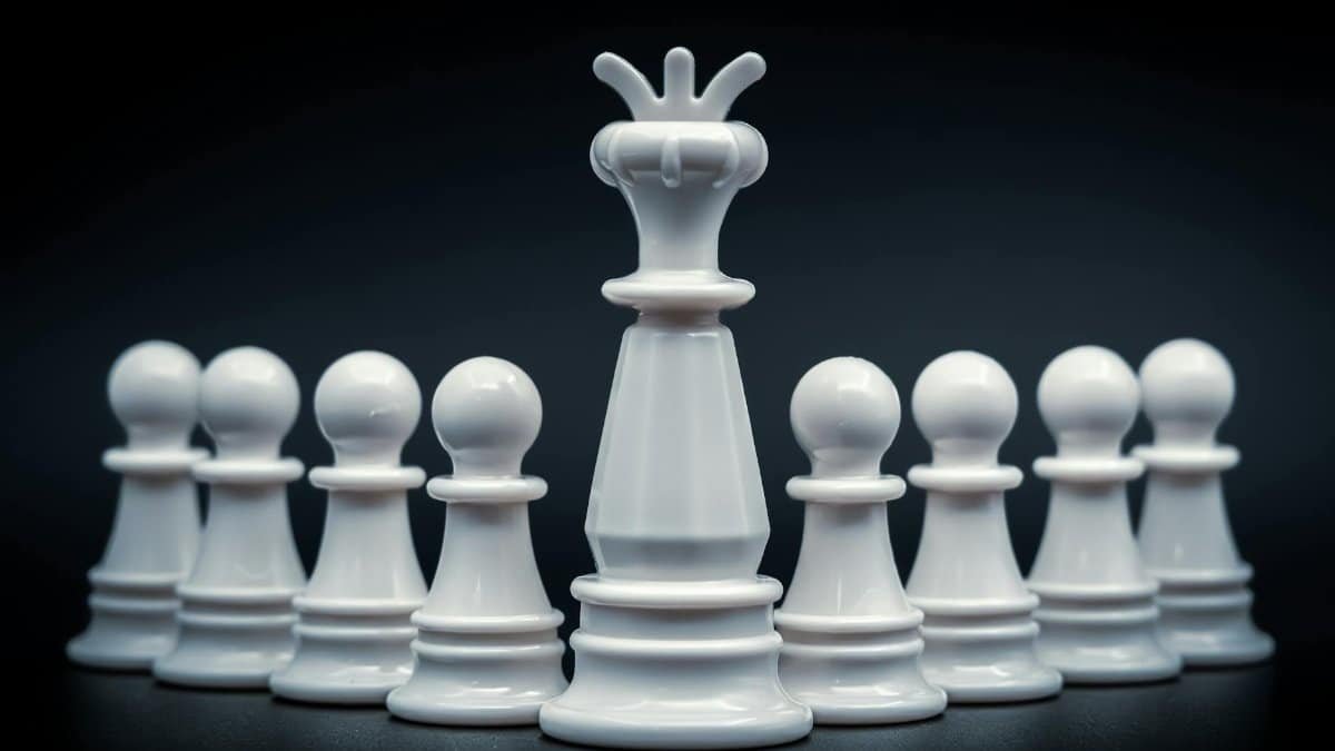 Close-up of white king and pawns on chessboard, symbolizing leadership and strategy.
