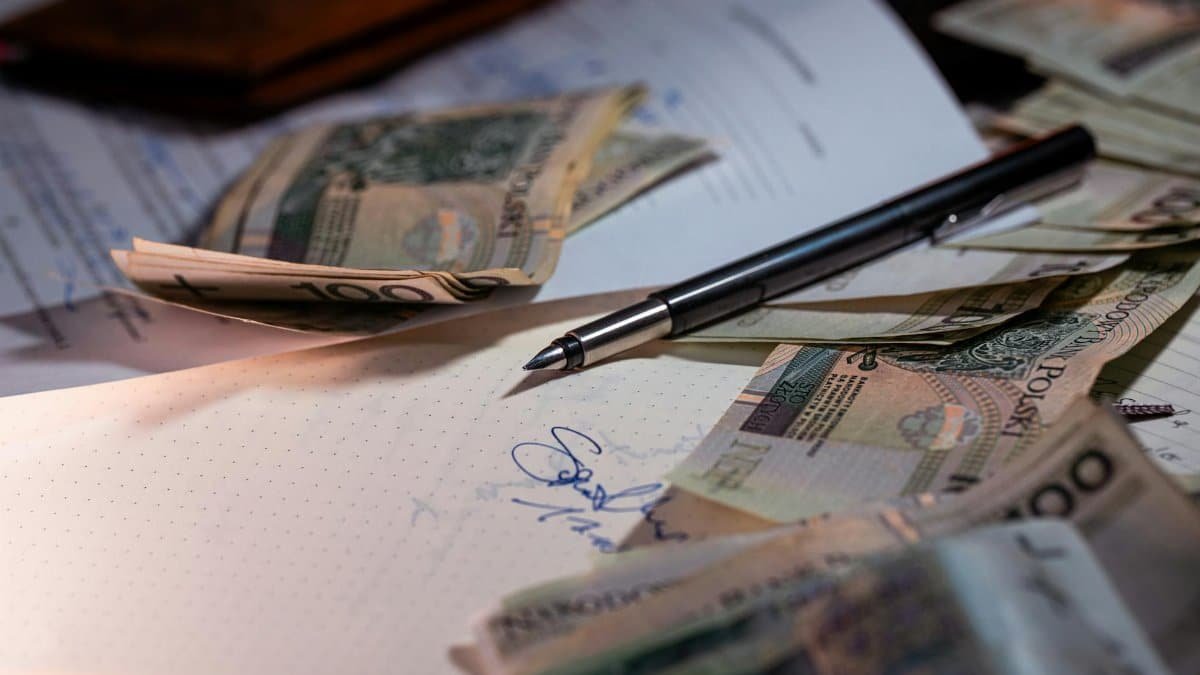 Overhead view of Polish banknotes, documents, and a pen on a desk, highlighting financial planning.