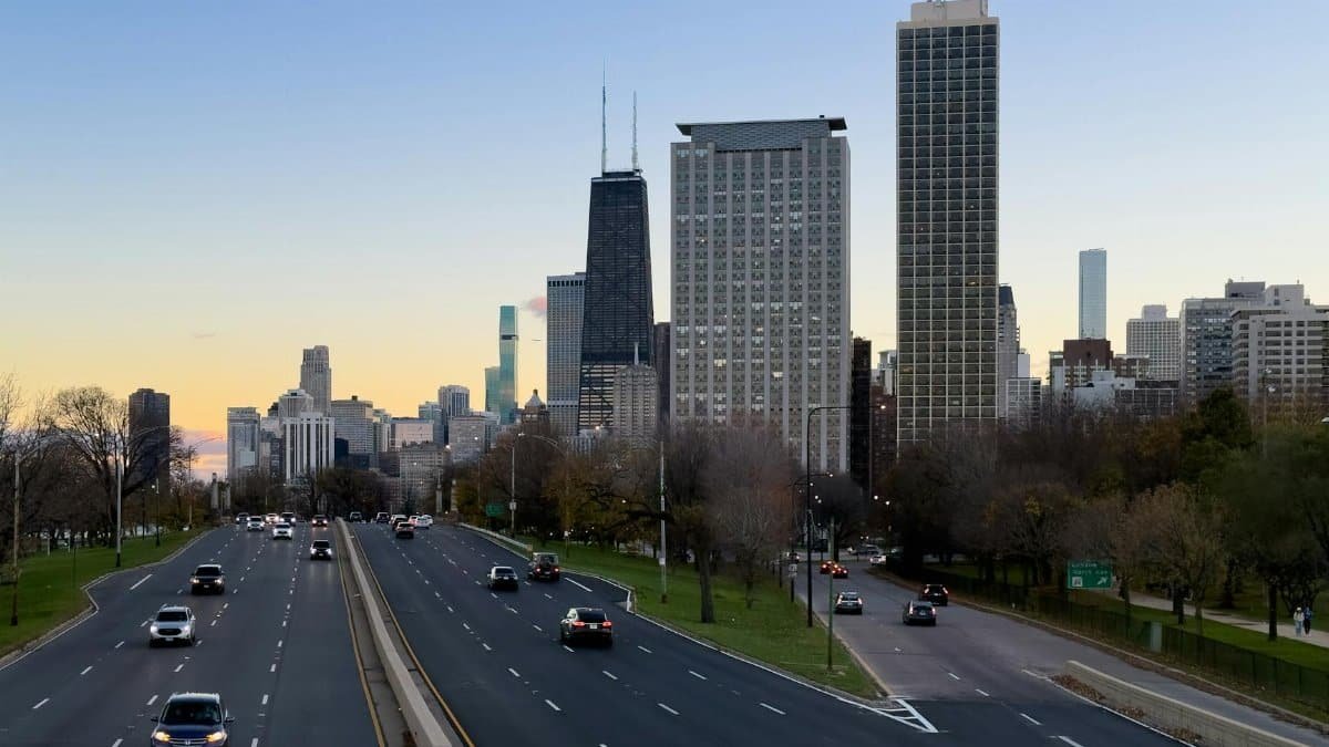 A view of downtown Chicago's skyline during sunset, featuring busy roads and modern architecture.