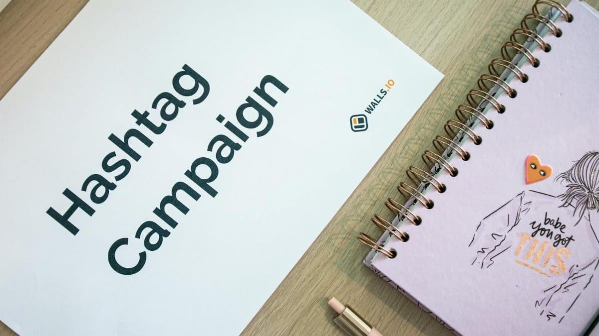 Creative desk setup featuring a hashtag campaign paper and a motivational notebook, ideal for marketing and planning themes.